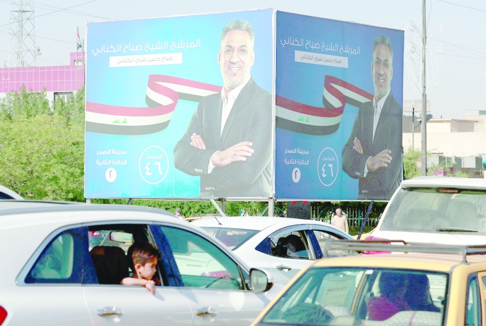 Cars drive in front of electoral billboards of a candidate for the upcoming parliamentary elections, in the Iraqi capital Baghdad's Sadr City neighbourhood, on Saturday. -- AFP