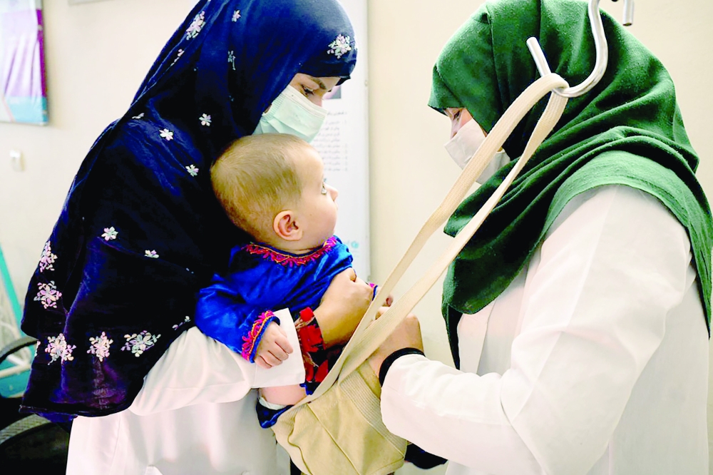 This picture shows a midwife (L) and a nutrition counsellor weighing a baby at the Tangi Saidan clinic in Daymirdad district of Wardak province. - AFP