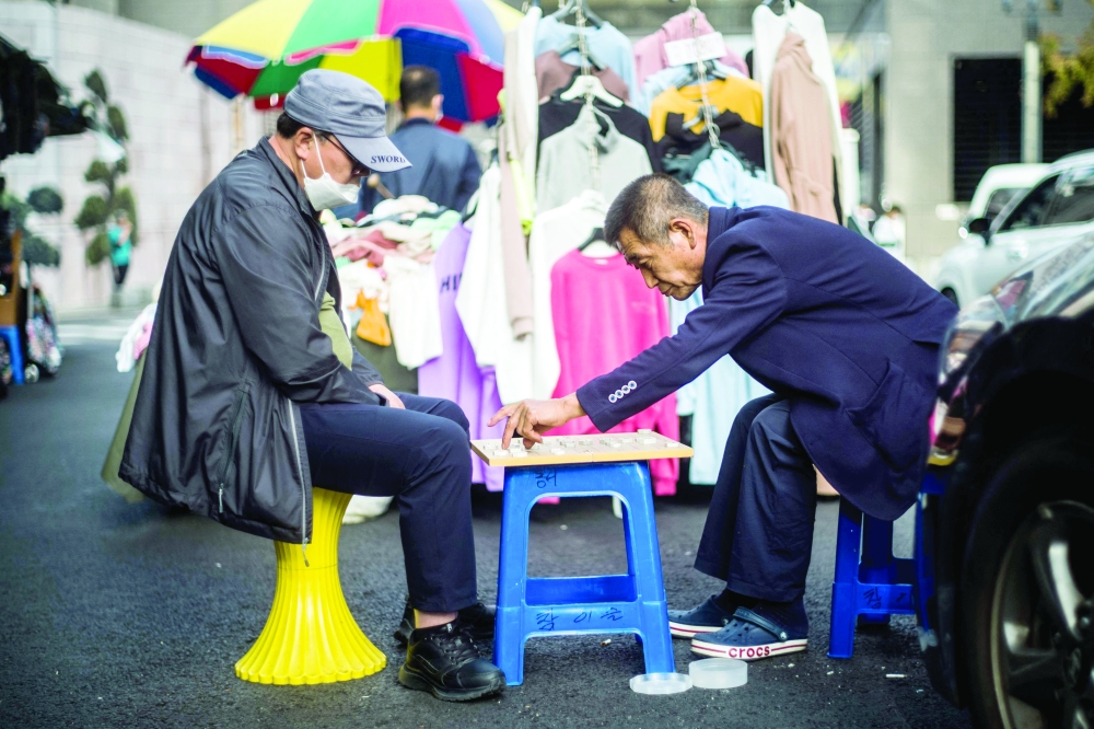 Men play a game of Janggi, also known as Korean chess, on a street in Seoul on Wednesday. - AFP