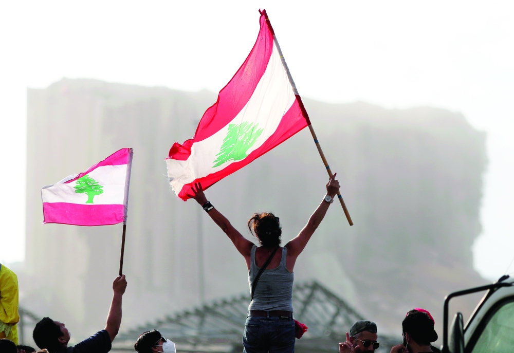 A file photo of demonstrators waving Lebanese flags during protests near the site of a blast at Beirut's port area, Lebanon. - Reuters