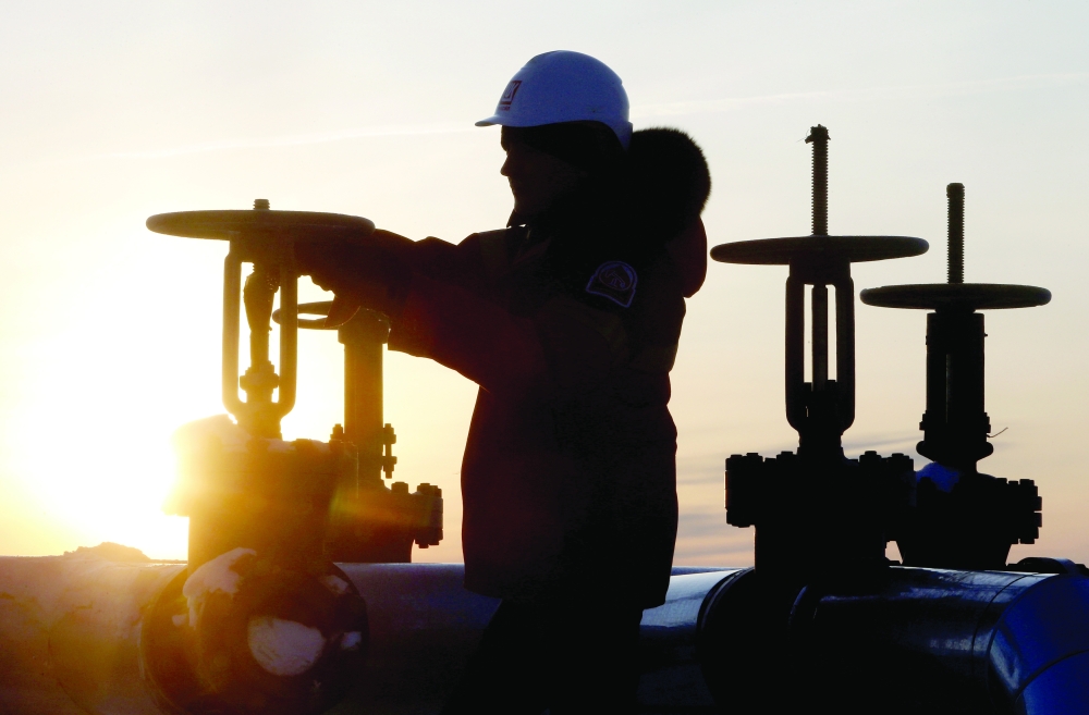 FILE PHOTO: Worker checks valve of oil pipe at Lukoil company owned Imilorskoye oil field outside West Siberian city of Kogalym
