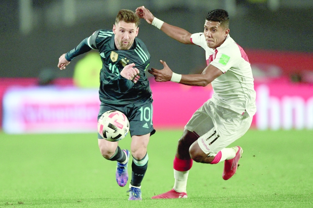 Argentina's Lionel Messi (left) and Peru's Raziel Garcia vie for the ball during their South American qualification match. -- AFP