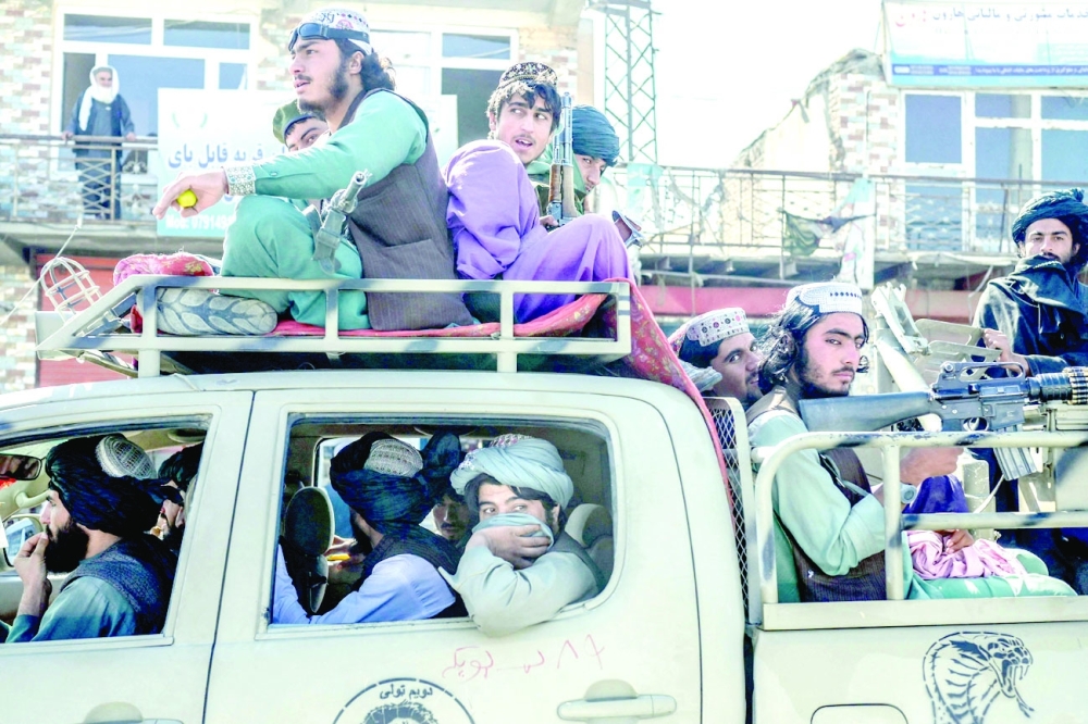 Taliban members drive along a road in the centre of Kabul. -- AFP

