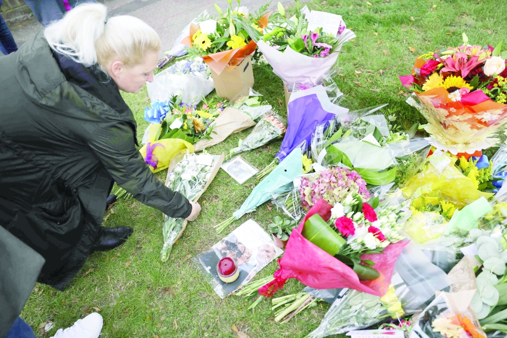 A Member of the public adds a bunch of flowers to floral tributes left at the scene of the fatal stabbing of Conservative British lawmaker David Amess, at Belfairs Methodist Church in Leigh-on-Sea, in southeast England. - AFP