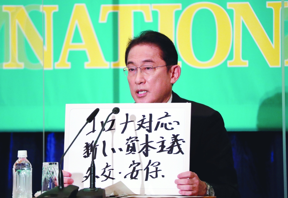 Japan's Prime Minister Fumio Kishida holds up a placard reading "Corona disease countermeasures, New Capitalism. Diplomacy and security" at a debate session at the Japan National Press Club in Tokyo, on Monday. - Reuters