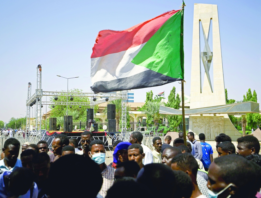 A protester holds a national flag during a sit-in demanding the dissolution of interim government, outside the presidential palace in central Khartoum, on Monday. - AFP
