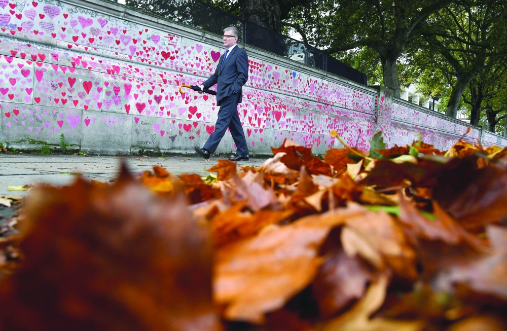 A man walks beside the National Covid Memorial Wall, a dedication of thousands of hand painted hearts and messages commemorating victims of the pandemic in London. - Reuters
