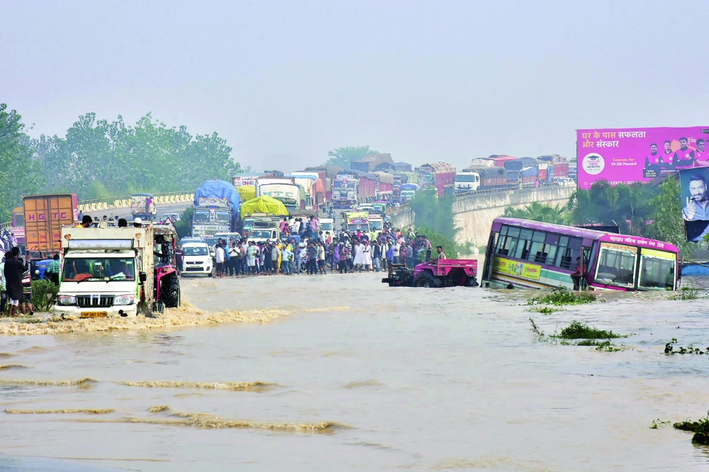 Commuters stand on a flyover on a flooded national highway after river Kosi overflowed following heavy rains near Rampur in India's Uttar Pradesh. - AFP