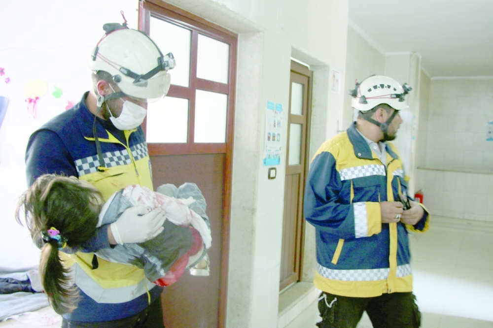 White Helmets members bring a child victim to hospital after a Syrian army shelling of residential areas in rebel-held Ariha, Idlib, on Wednesday .- Reuters