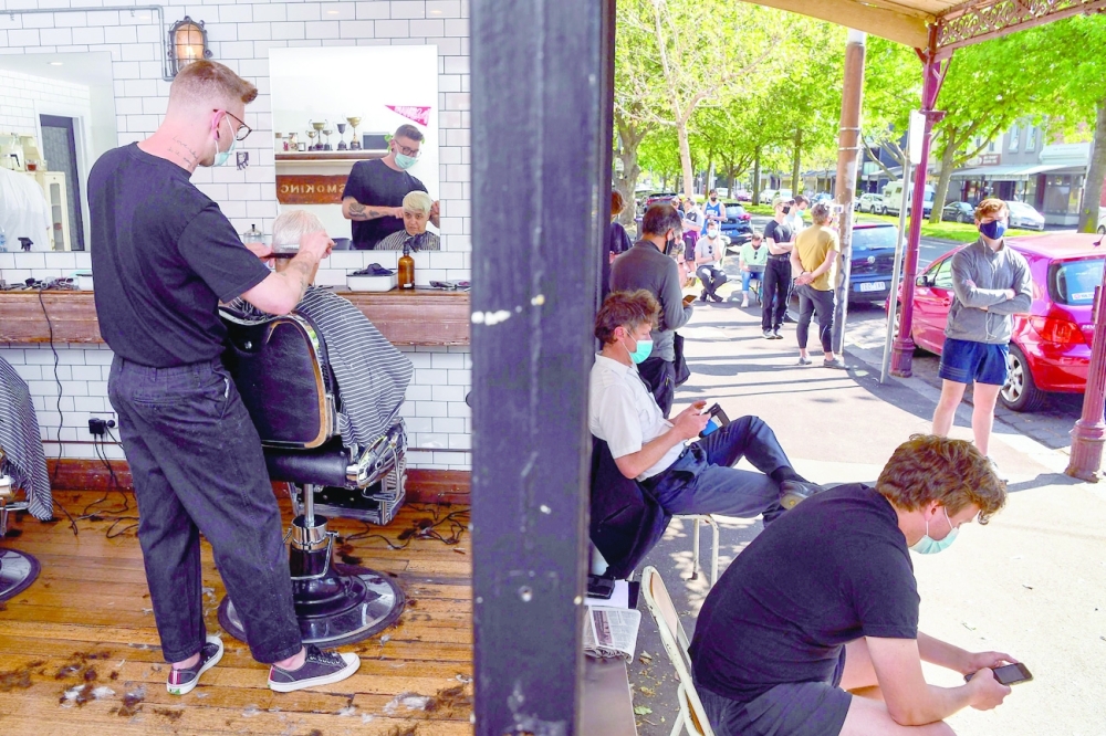 A barber gives a haircut as other customers wait outside in a queue that began as early as 4:30am in Melbourne, Australia, on Friday. - AFP