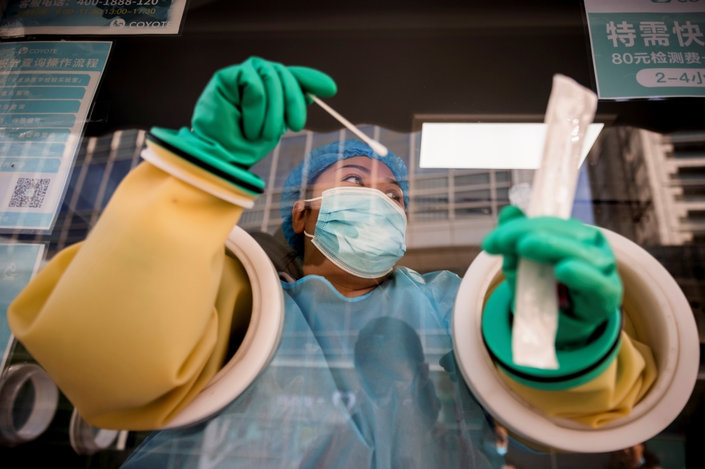 A medical staff administers a nucleic acid test at a booth on a street in Beijing, China