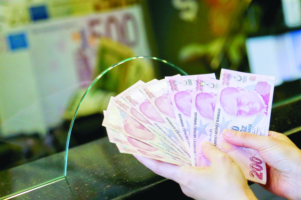 A money changer holds Turkish lira banknotes at a currency exchange office in Ankara. - Reuters