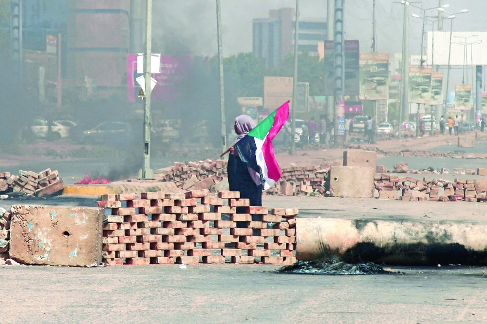 A demonstrator carrying a national flag walks by roadblocks on a street in Khartoum on Tuesday. - AFP