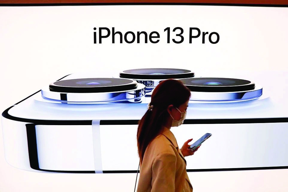 

A woman wearing a face mask walks past an image of an iPhone 13 Pro at an Apple Store in Beijing. - Reuters