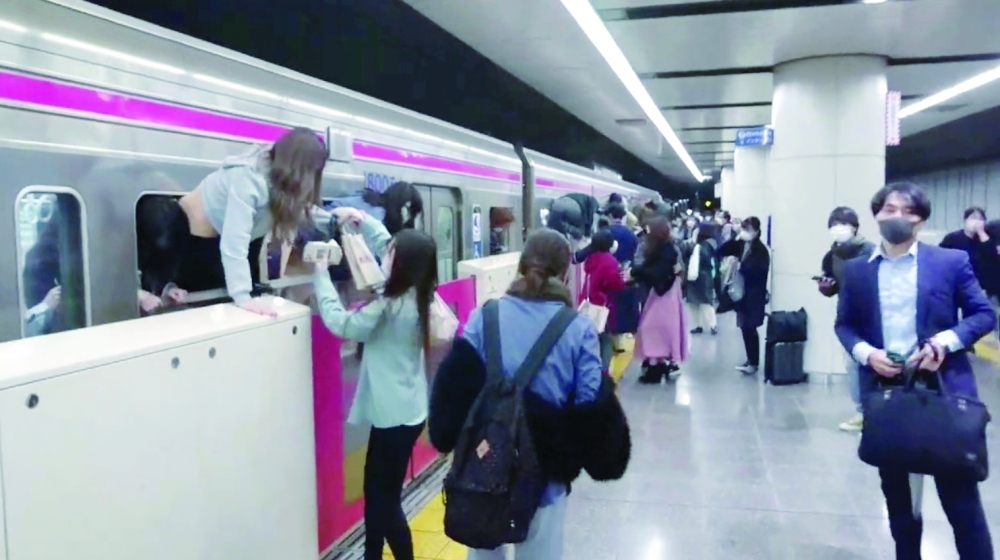 People escape through windows of a Tokyo train line following a knife, arson and acid attack, in Tokyo on Sunday. - Reuters