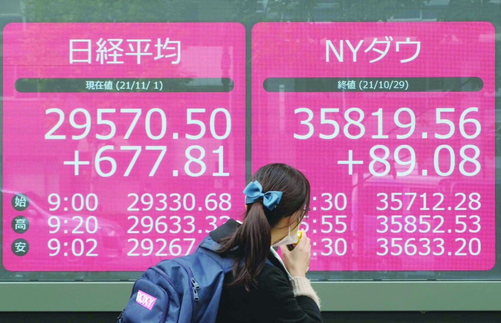 A pedestrian walks past an electronic quotation board displaying share prices of the Tokyo Stock Exchange in Tokyo. - AFP
