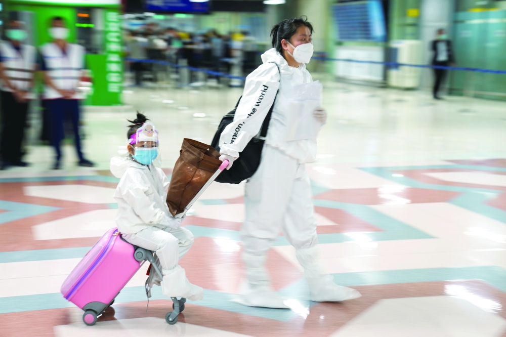 Chinese tourists wearing protective suits arrive at Suvarnabhumi Airport in Bangkok, on Monday. - Reuters