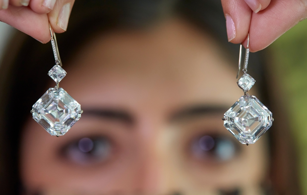 A staff member holds a pair of diamond earrings, weighing 25.88 carats, during a preview at Sotheby's, before their auction sale in Geneva, Switzerland
