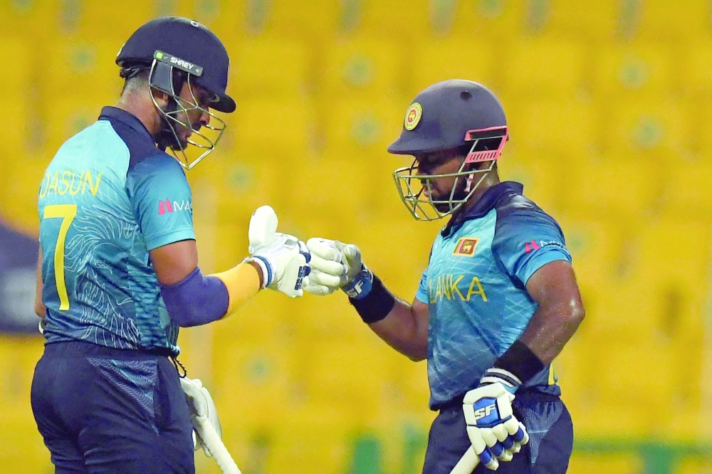 Sri Lanka's Charith Asalanka (L) bump fist with captain Dasun Shanaka (R). -- AFP