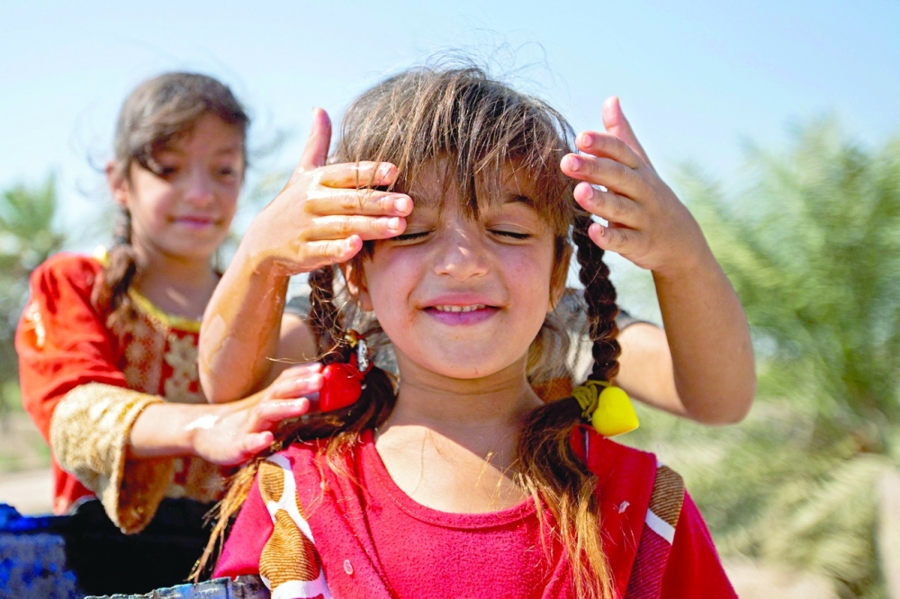 Children play in the vicinity of the Nahr Bin Omar oilfield in Iraq's southern province of Basra. - AFP