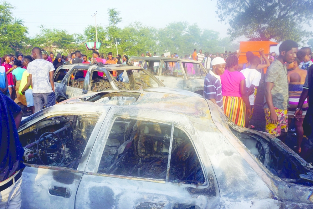 People look on at burnt cars in the aftermath of a fuel tanker explosion in Freetown on Saturday. - AFP