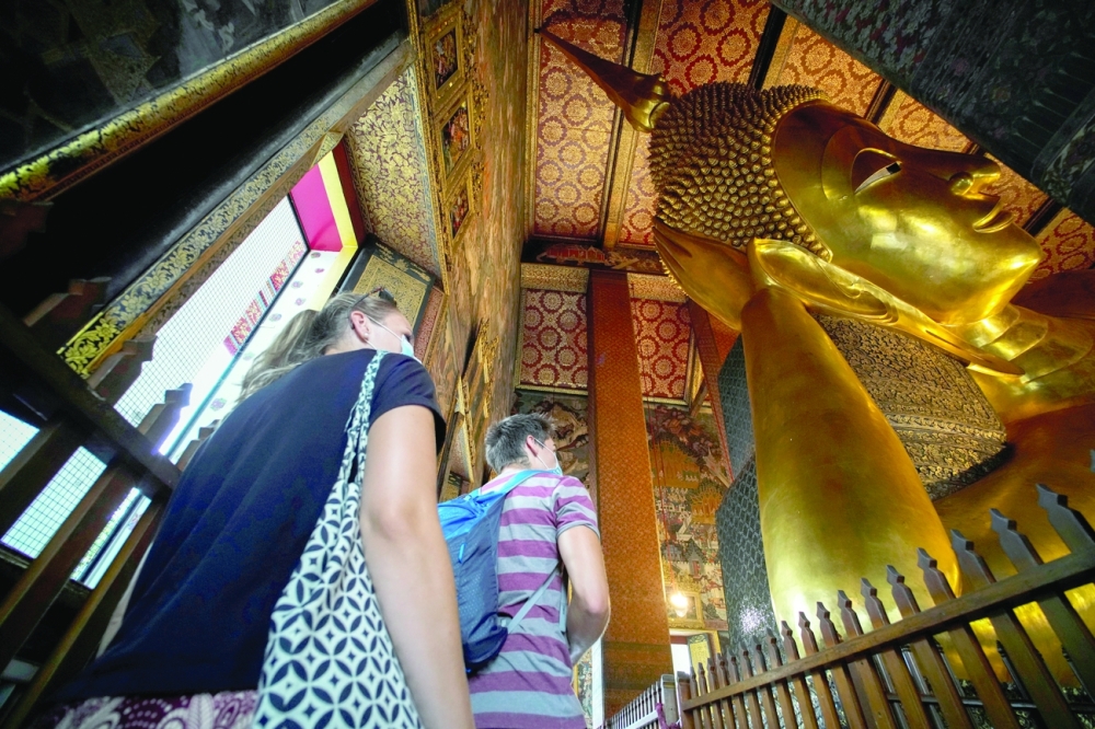 Foreign tourists are seen next to the Reclining Buddha at Wat Pho in Bangkok, Thailand, last Tuesday. - AFP