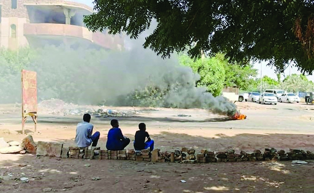 Young Sudanese sit on a street barricades built overnight by demonstrators in Khartoum. - AFP