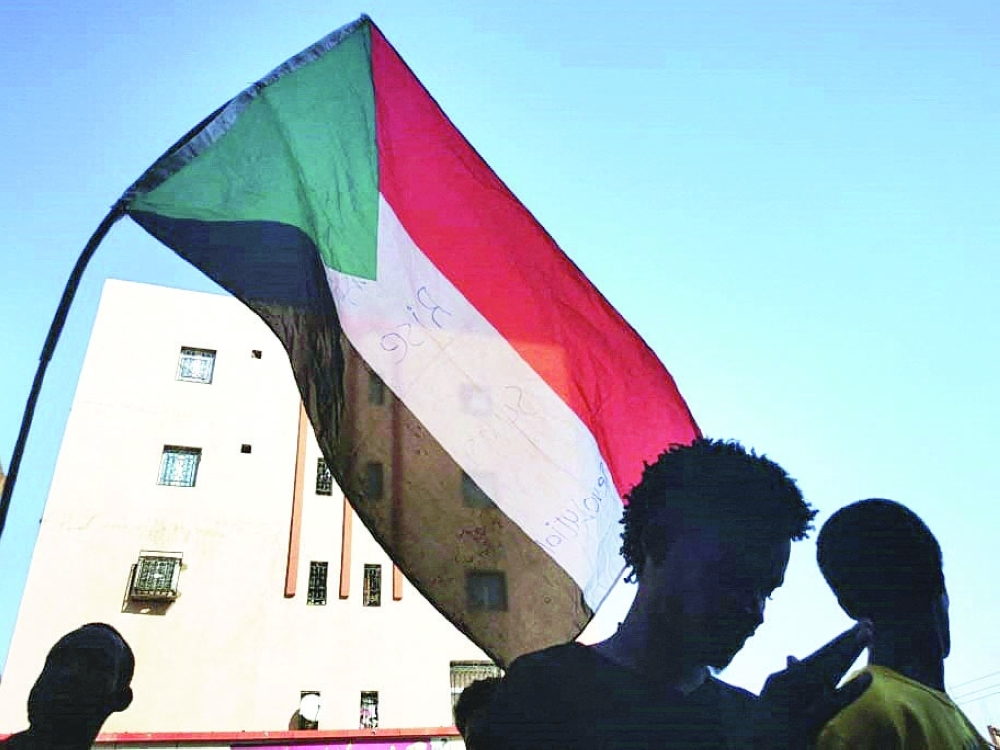 Sudanese youth wave a national flag as they protest in the streets of Khartoum. - AFP
