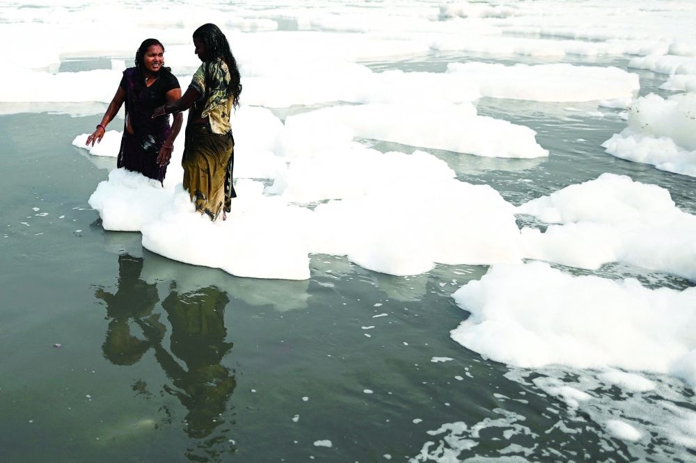 Women take a dip in the waters of Yamuna river as a part of rituals for the upcoming festival of Chhat puja in New Delhi. - AFP