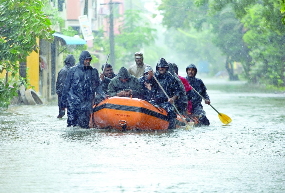 Members of Fire and Rescue Services paddle their boat through a water-logged road during heavy rains in Chennai, India, on Thursday. - Reuters