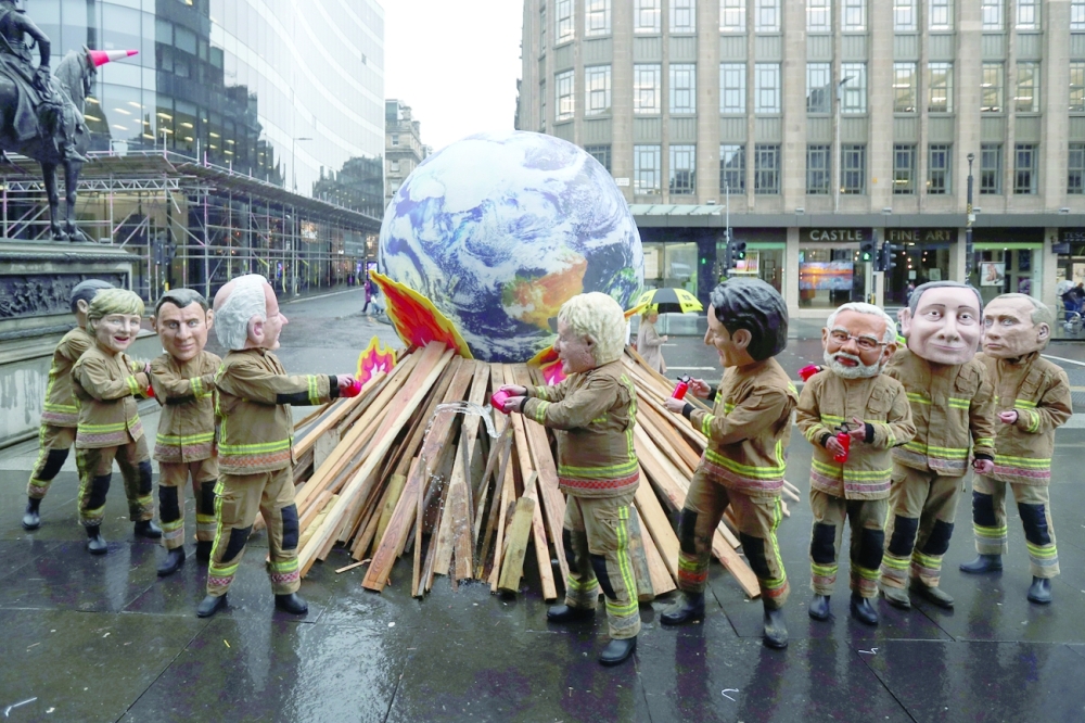 Oxfam campaigners dressed in the roles of "ineffective fire-fighting world leaders" pose for a photo during a media opportunity near the UN Climate Change Conference in Glasgow, Scotland, on Friday. - Reuters