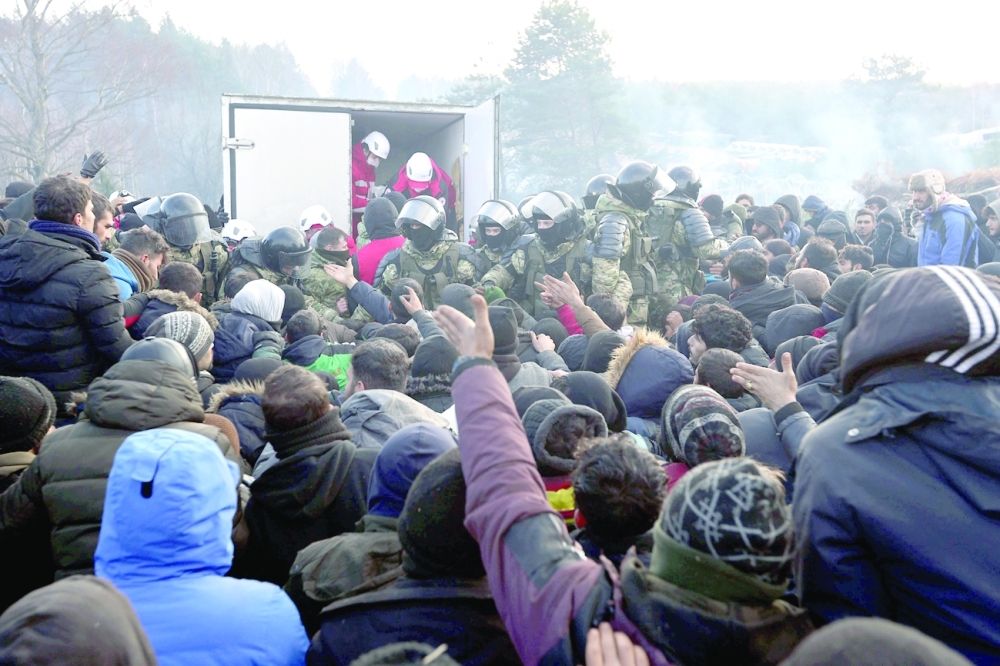 Belarusian service members stand guard as migrants attempt to approach a minivan during the distribution of humanitarian aid in a makeshift camp on the Belarusian-Polish border in the Grodno region, Belarus on Friday. - Reuters 