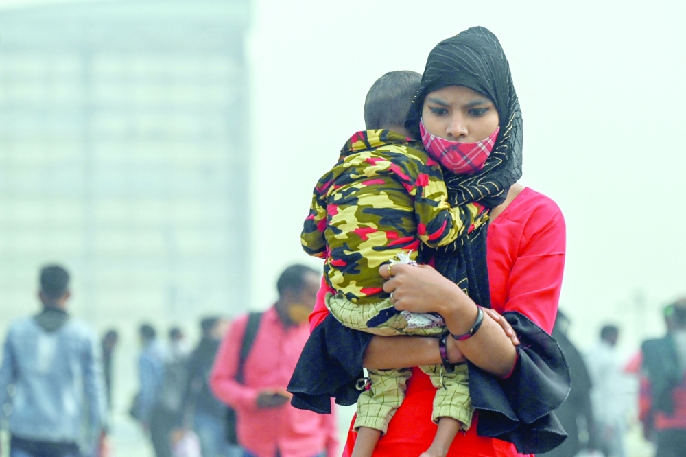 A woman carrying a child walks across a footbridge under heavy smoggy conditions in New Delhi on Friday.-- AFP