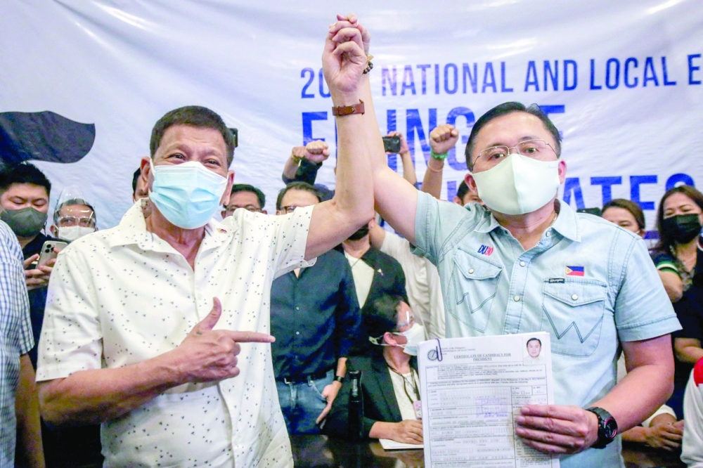 Philippine President Rodrigo Duterte (L) raises the hand of senator Christopher 'Bong' Go after he filed his candidacy for president in the 2022 elections in Manila on Thursday. -- AFP 


