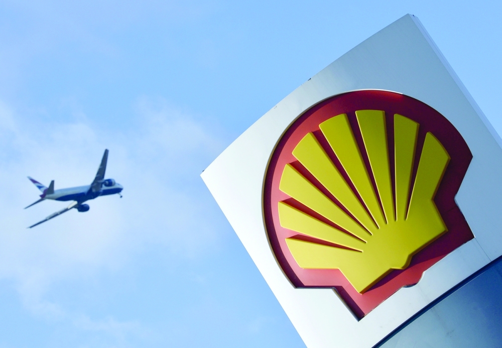 A passenger plane flies over a Shell logo at a petrol station in west London. —  Reuters