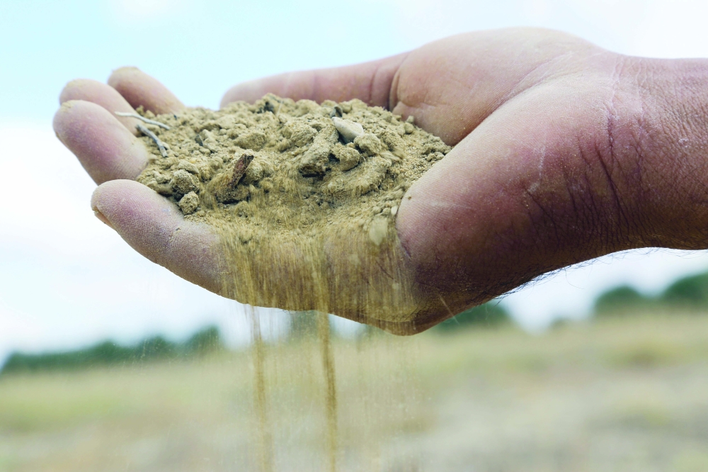 A farmer holds a handful of soil parched because of drought in Tunisia's east-central area of Kairouan. - AFP