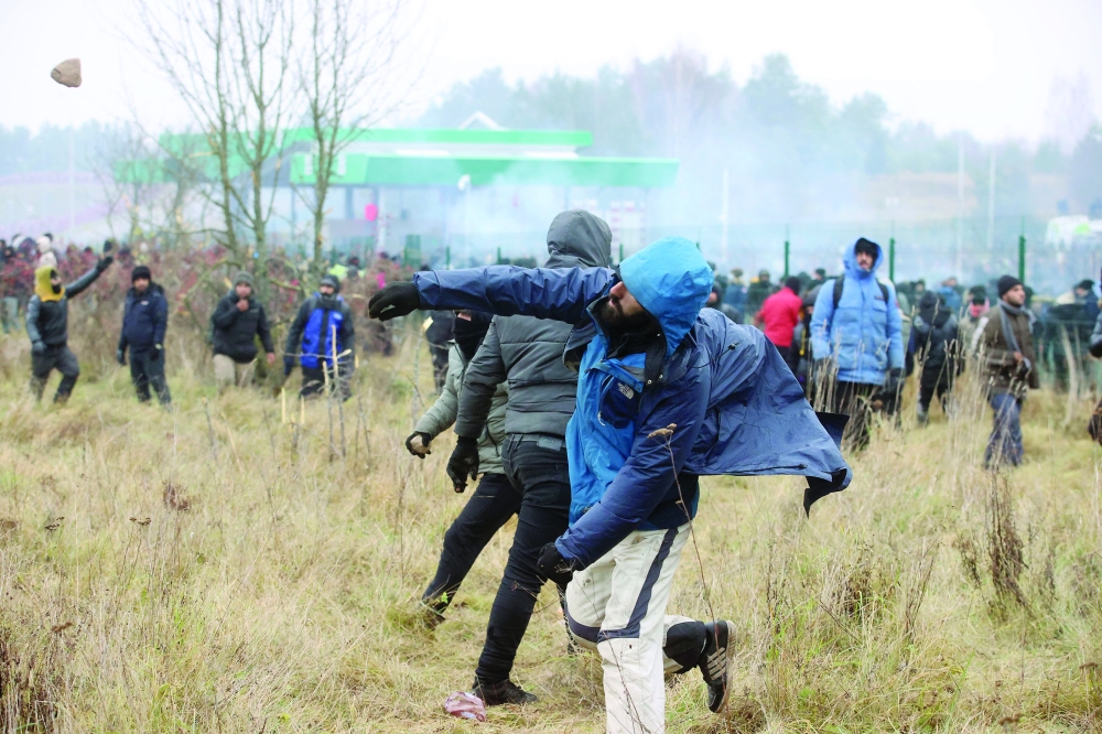 A man throws a stone in the direction of a border fence and Polish law enforcement officers, as migrants attempt to cross the Belarusian-Polish border at Bruzgi-Kuznica checkpoint in the Grodno region, Belarus, on Tuesday. — Reuters