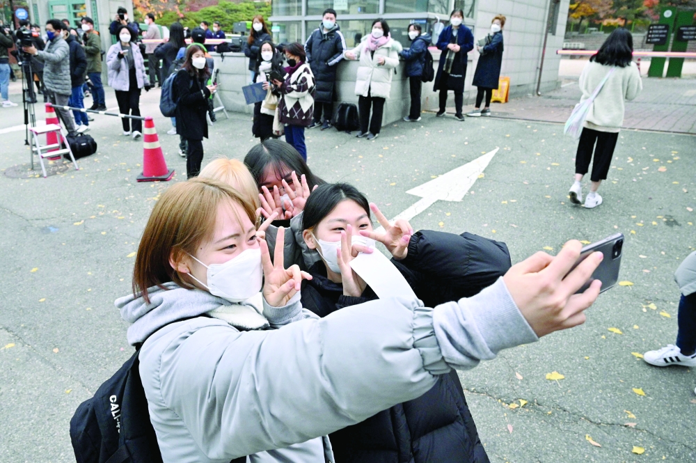 Students take selfies as they arrive to sit for the annual college entrance exams outside the Ehwa Girls Foreign Language High School in Seoul on November 18, 2021. (Photo by Anthony WALLACE / AFP)
