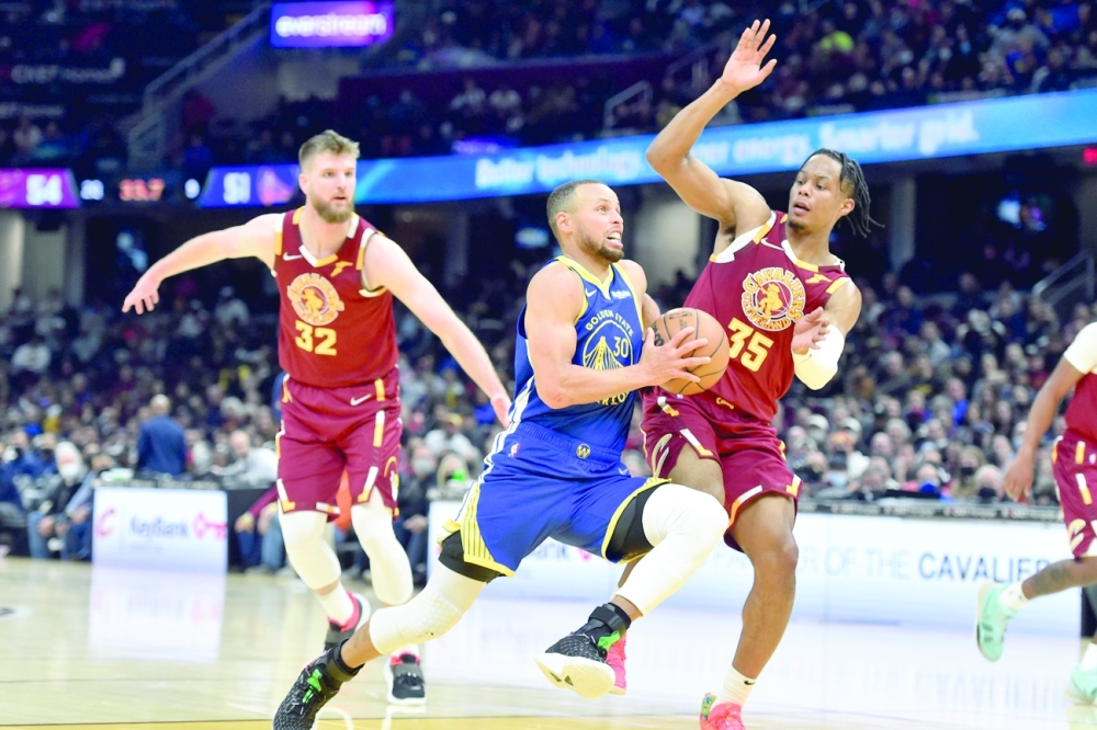 Golden State Warriors guard Stephen Curry (30) drives against Cleveland Cavaliers forward Dean Wade (32) and forward Isaac Okoro (35) in the second quarter at Rocket Mortgage FieldHouse. -- USA Today Sports
