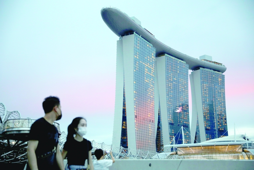People wearing face masks pass the Marina Bay Sands hotel during the Covid outbreak, in Singapore on Thursday. - Reuters