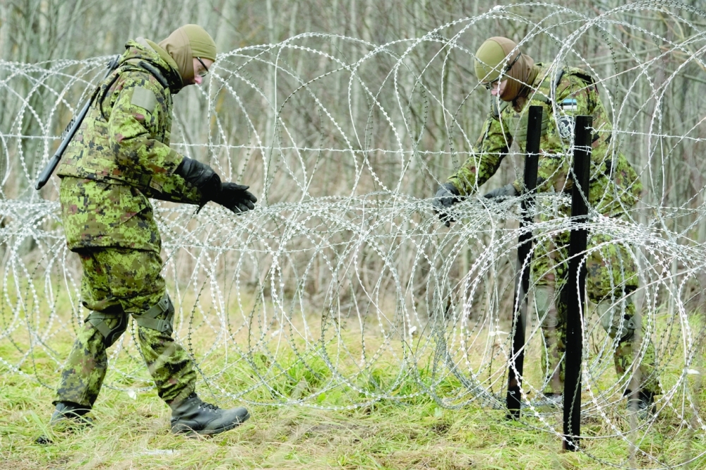 Estonian army reservists build a temporary razor wire fence on a border with Russia during a snap military exercise Okas 2021 near Meremae, Estonia. - Reuters