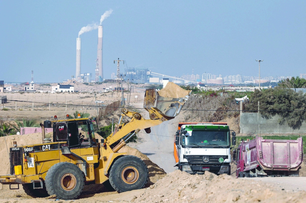 An excavator clears land at a road section undergoing expansion north of Gaza City. - AFP 