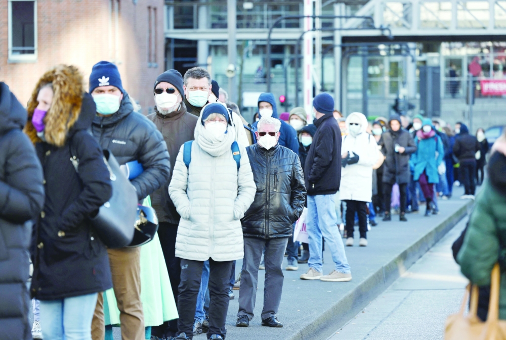 People wearing face masks stand in a queue to get vaccinated in the Philharmonic Hall in Hamburg. - AFP