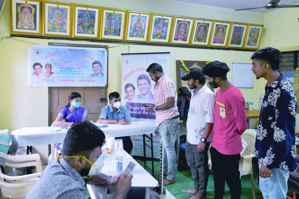 Narayana Nethralaya Eye Hospital employees help volunteers fill eye donation pledge forms during an event organised in memory of late Indian film actor Puneeth Rajkumar in Bangalore. - AFP