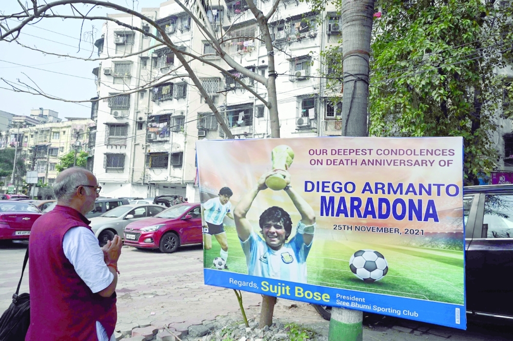 A football fan pays his homage next to a poster fixed to observe the first death anniversary of late Argentine soccer legend Diego Armando Maradona in Kolkata. -- AFP
