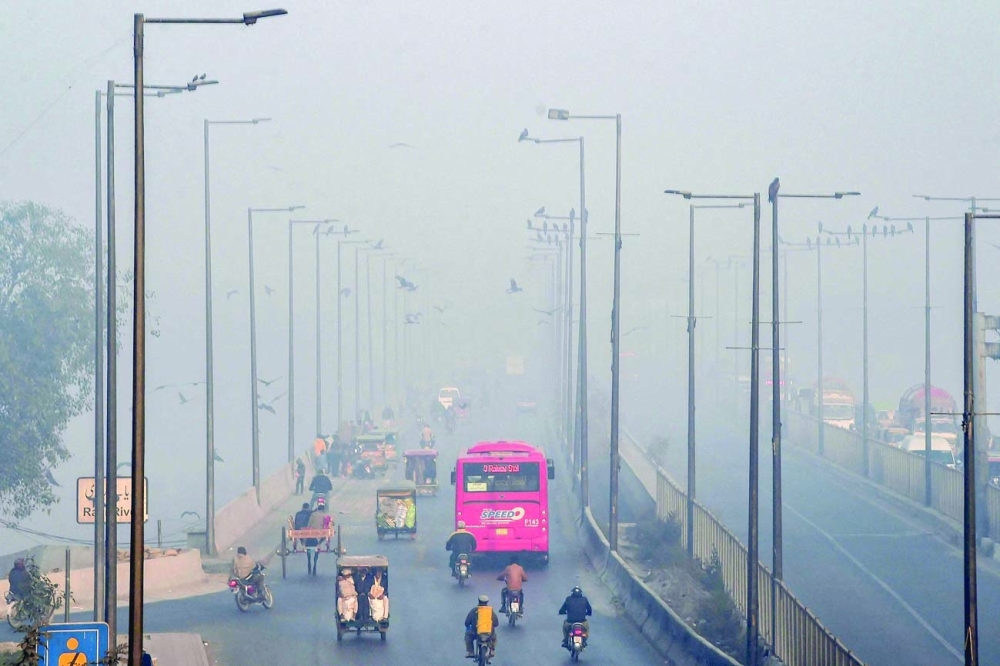 Commuters make their way along a road amid smoggy conditions in Lahore on Wednesday. — AFP