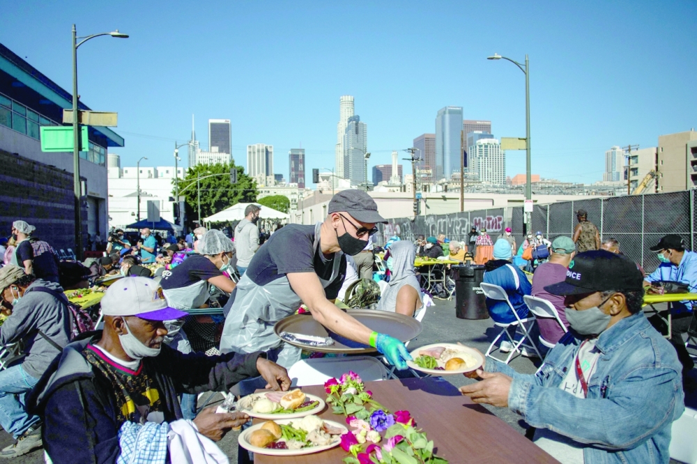 A volunteer serves a plate of food to a homeless man during the traditional Thanksgiving meal served by the non-profit Midnight Mission to nearly 2,000 homeless people in the Skid Row neighbourhood of downtown Los Angeles on Thursday. - AFP