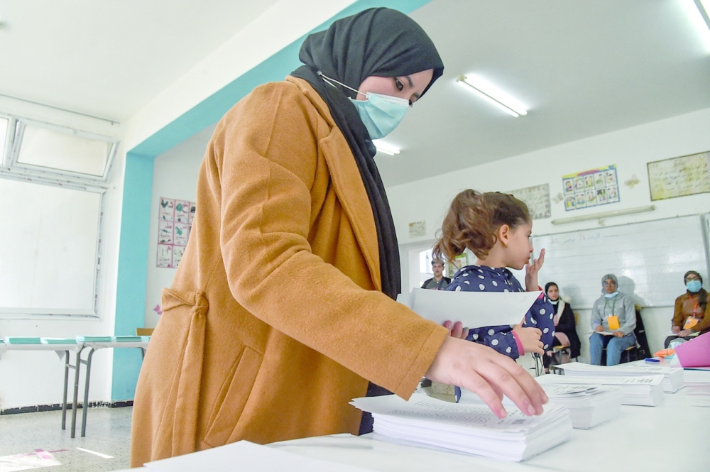 A woman picks up a ballot while voting in the Algerian local elections at a polling station in the capital Algiers. - AFP 