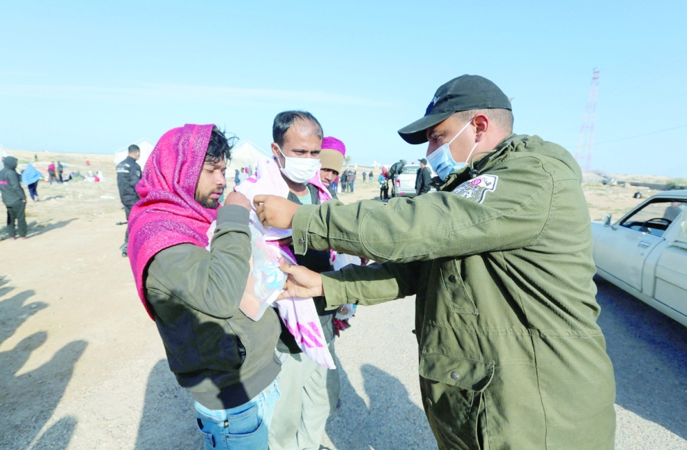A member of Tunisia's national guard delivers rations to migrants rescued during an attempted crossing of the Mediterranean by boat in southern Tunisia near the border with Libya. - AFP