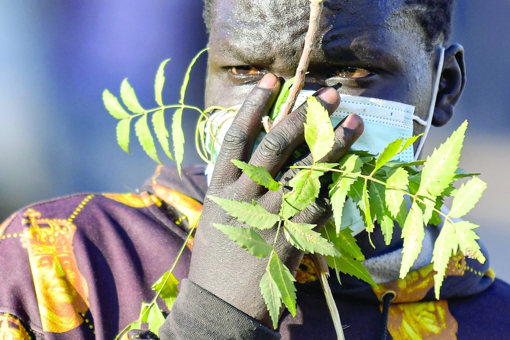 A Sudanese anti-coup protester covers his face with a plant, to protect from teargas, during a demonstration in the "Street 40" of the capital's twin city of Omdurman. - AFP